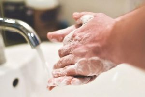 Washing hands with lathered soap under a faucet