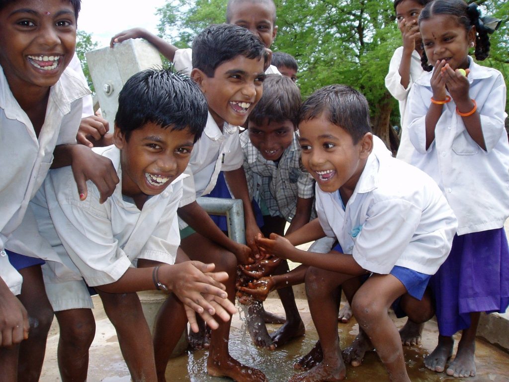 Children celebrating a new hand water pump
